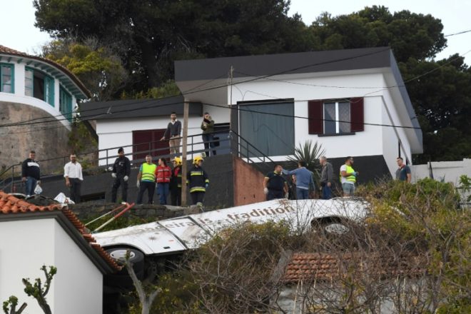 Varias personas miran los restos de un autobús de turistas accidentado en Caniço, en la isla portuguesa de Madeira, el 17 de abril de 2019. Foto: AFP.